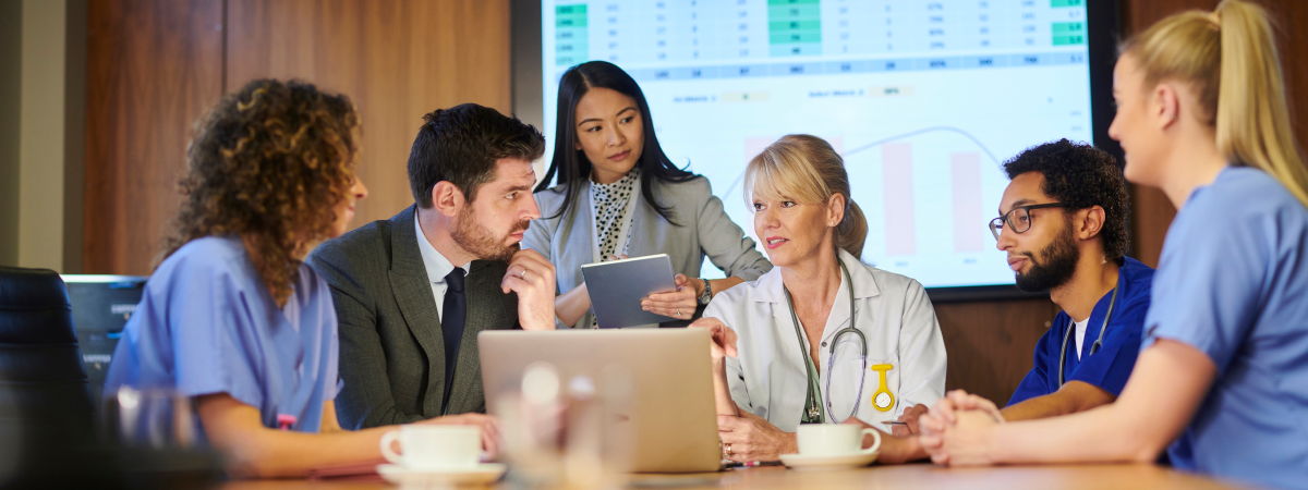 Photography of a group of medical doctors having a meeting with a man and a woman in business attire.